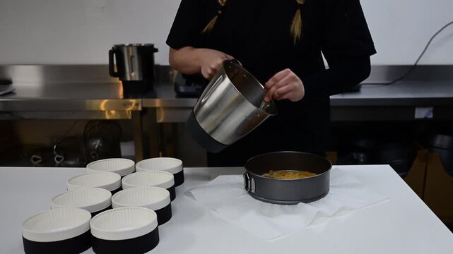 Female pastry chef pouring cheesecake base into a baking pan