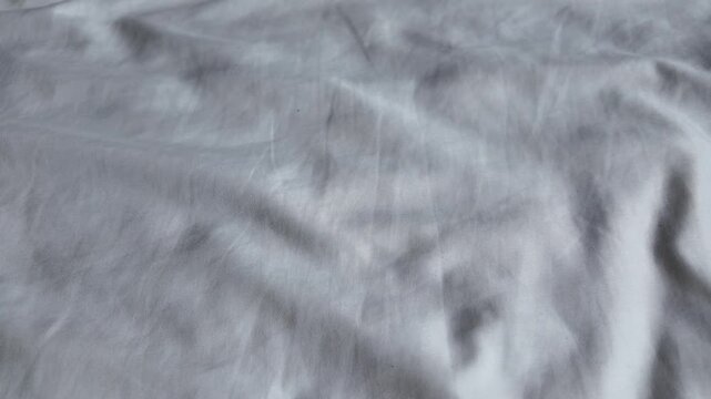 Smooth, wrinkled white fabric surface showcases delicate textures and soft shadows, creating light and inviting atmosphere perfect for design applications.