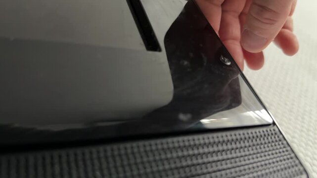 Person pressing power button on electronic device close up at home, turning device on, everyday interaction, technology use concept