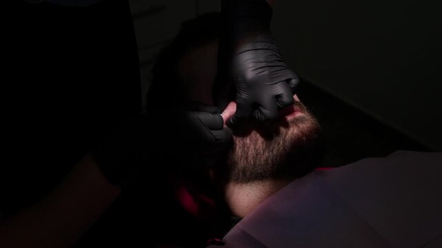 Cosmetologist injecting hyaluronic acid into man's cheek