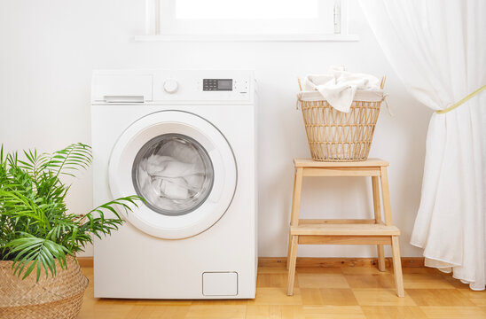 Laundry room interior with dirty clothes in wicker basket near washing machine