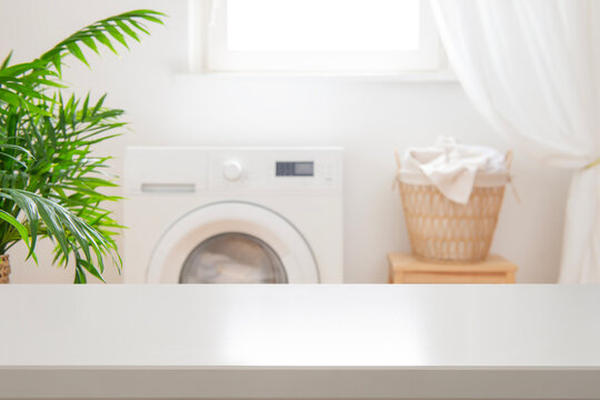 White blank table for design and montage on blurred laundry room background