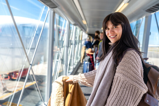 Woman smiling boarding airplane connecting to jet bridge