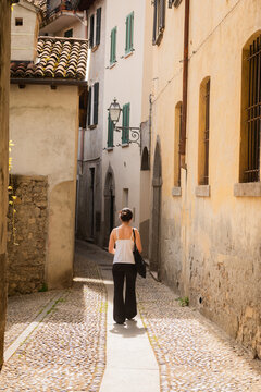 rear view of woman walkin in ancient narrow italian alley in yellow tones