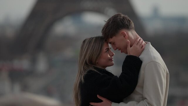 A young couple embraces in Paris France with the Eiffel Tower visible in the background The handheld shot captures the romantic moment as the lovers hug. This clip is perfect for travel romance and Eu