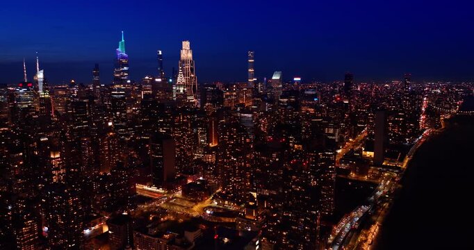 Hectic traffic on the luminous streets of New York City. Skyscrapers top lit by neon lights against dark sky. Never-sleeping metropolis at night.