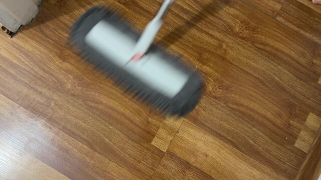 Person mopping wooden floor with mop, cleaning and maintenance concept, washing surface and removing dirt indoors