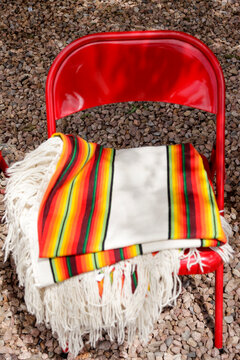 Colorful woven blanket draped over red chair