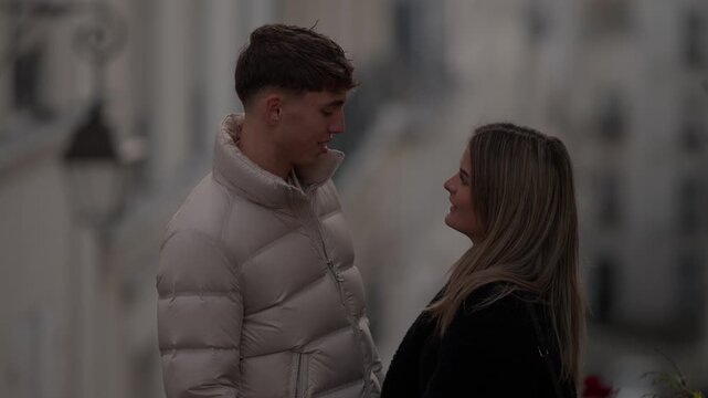 A young couple in Paris France share a loving moment The clip features a panning shot of the man and woman dressed in winter coats standing on a European street looking at each other with affection.