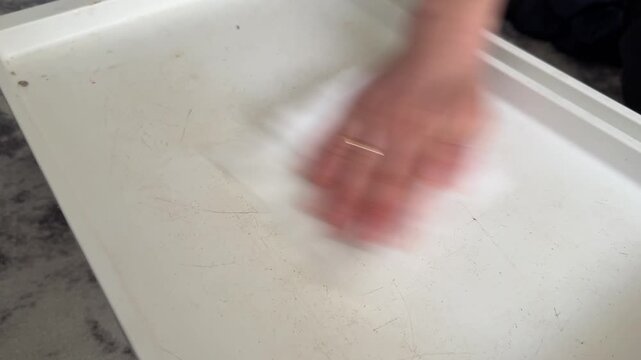 Person wiping folding table with cloth, cleaning surface and household hygiene concept, maintaining furniture cleanliness indoors