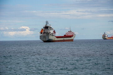 Fototapeta premium Cargo ships anchored in calm ocean under partly cloudy sky