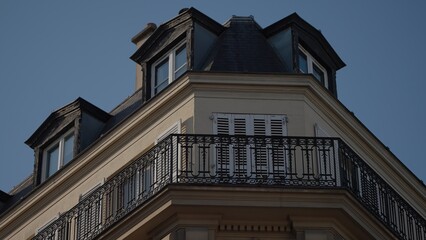 Obraz premium A close-up view of Parisian architecture in France showcasing a building with a balcony and shutters. This image can be used for travel architecture or real estate purposes.