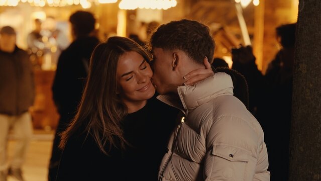 A romantic couple shares a kiss in Paris France at night illuminated by soft bokeh lights. This image captures a moment of affection and love suitable for travel lifestyle or relationship themes.