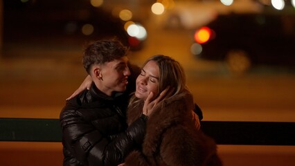 Fototapeta premium A romantic couple is embracing on a bench at night in Paris France with bokeh lights in the background. This image can be used for travel tourism romance or relationship concepts.