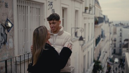 Fototapeta premium A young couple embraces on the hill of Montmartre in Paris France with a cityscape and Parisian architecture in the background The image conveys love romance and urban lifestyle in a European travel d