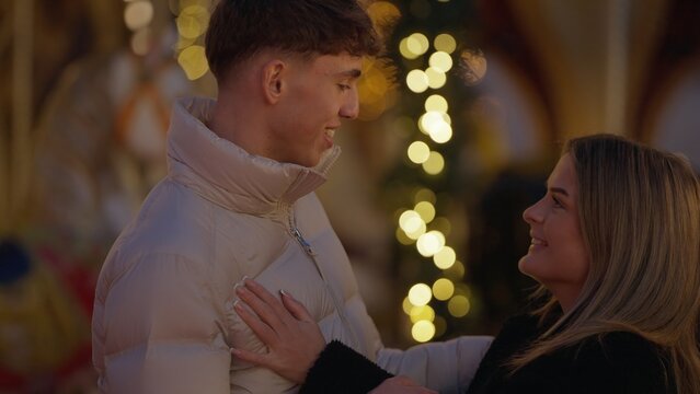 A romantic couple in Paris France at night surrounded by Christmas lights sharing love and affection The young man and woman are smiling dressed in winter fashion enjoying a romantic moment togetherne