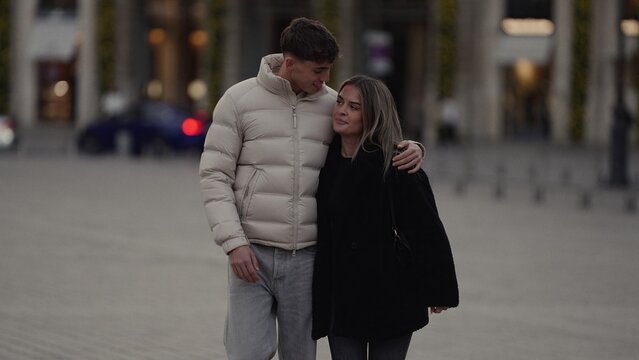 A young couple embraces affectionately on a Paris street sharing a loving gaze The image showcases urban tourism romantic relationships and stylish winter fashion in a European city.