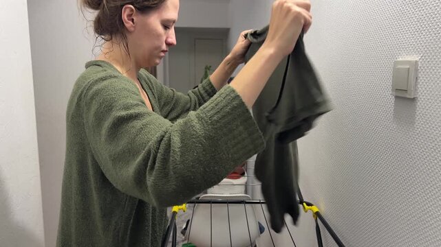 Woman hanging clothes on drying rack, laundry routine and fabric care concept, indoor household activity and daily organization
