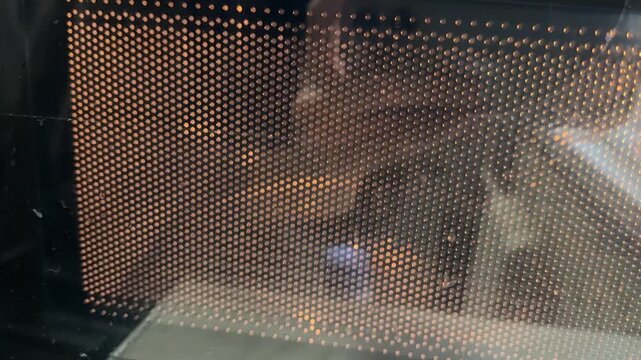 microwave oven heating food behind glass door, kitchen appliance in operation close up