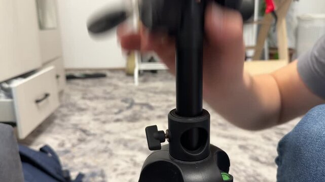 Hand mounting tripod head onto camera stand, assembling photography support equipment for video production concept