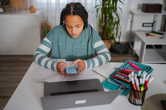 Student distracted by smartphone while doing homework