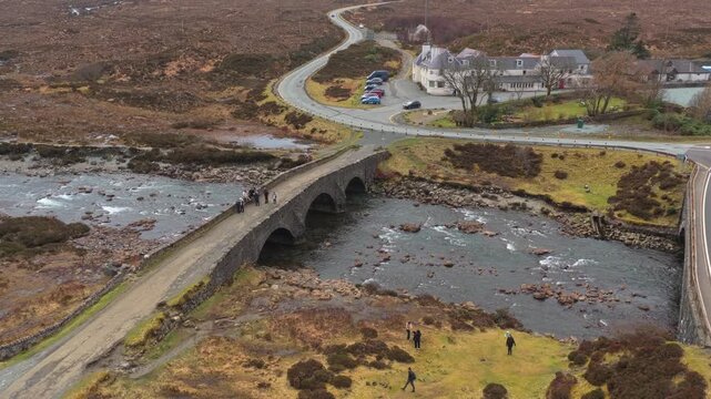 Aerial view of the historic sligachan old bridge, an ancient stone structure over a river, surrounded by the vast moorland of the isle of skye