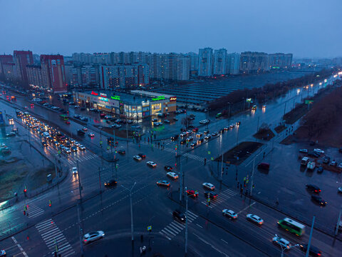 Drone shot captured with DJI Mini 2 overlooking the intersection of Shirotnaya Street and Permyakova Street in Tyumen, Russia, during twilight hours. The Shirotny shopping mall (Torgovy tsentr