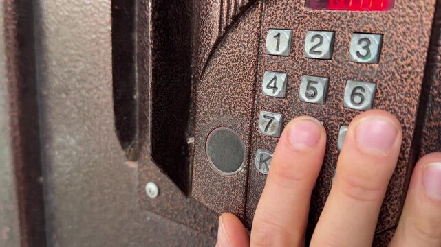 Person pressing button on door intercom keypad outdoors to open entrance door, access control action, security system use, everyday routine