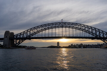 Fototapeta premium Sydney Harbour Bridge at sunset with golden reflections on the water