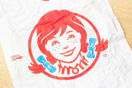 Tbilisi, Georgia - January 9, 2026: Horizontal photo close up. Paper packaging with logo of fast food cafe Wendy's, redhead girl face with braids with blue bows. Concept of pick up order, diet, eat