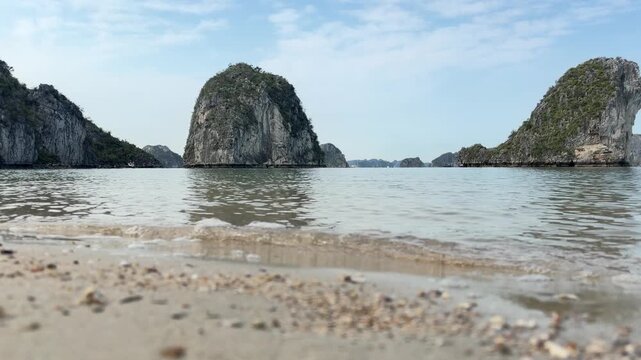 Limestone karst islands rising from calm waters of Ha Long Bay in Vietnam, serene coastal travel landscape