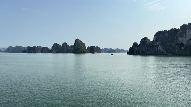 scenic panoramic view of limestone karsts at halong bay vietnam with calm turquoise waters and small fishing boat silhouettes