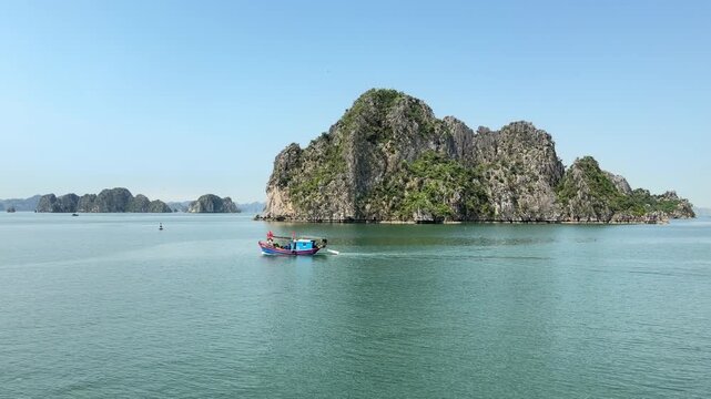 Small wooden boat navigating calm turquoise waters of Halong Bay, limestone karsts, serene coastal travel destination, tranquil seascape