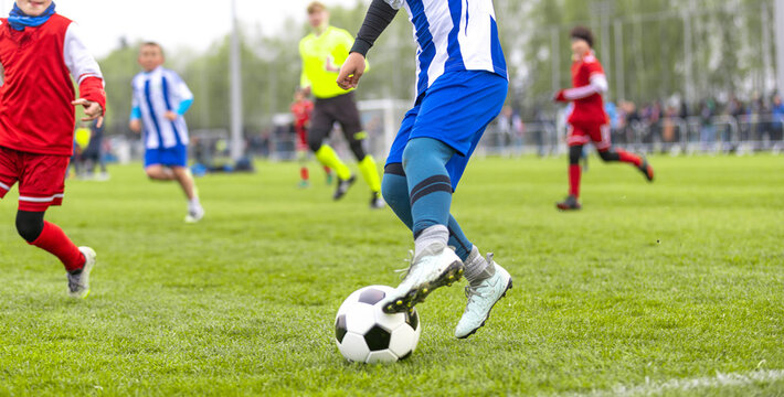 Junior Soccer Action Close-Up of Players Dribbling During Competitive Match - Youth Football Tournament with Athletes in Blue and Red Uniforms