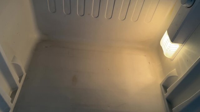 empty mini refrigerator interior with light on, clean storage compartment for food or drinks, household appliance concept