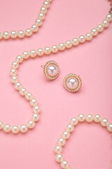 Obraz premium Beautiful pearl earring and necklace on pink background. Vertical photo