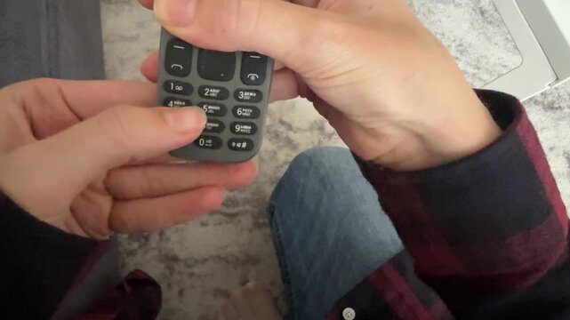 Hand pressing buttons on old mobile phone keypad, retro communication device and vintage technology concept