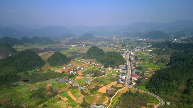 Aerial view of rural landscape with rice fields, limestone hills, and small villages in Ha Giang, Vietnam. Mountain countryside showcasing traditional farming and natural beauty in northern Vietnam.