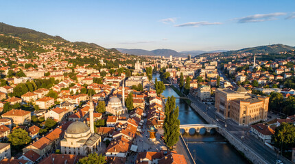 Obraz premium Aerial view of Sarajevo's historic old town with mosques and a river at sunset.