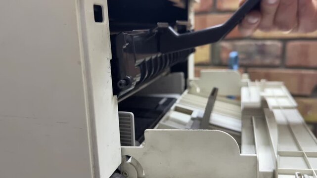 Person removing and inserting printer cartridge, maintenance and replacement concept, working with office equipment indoors