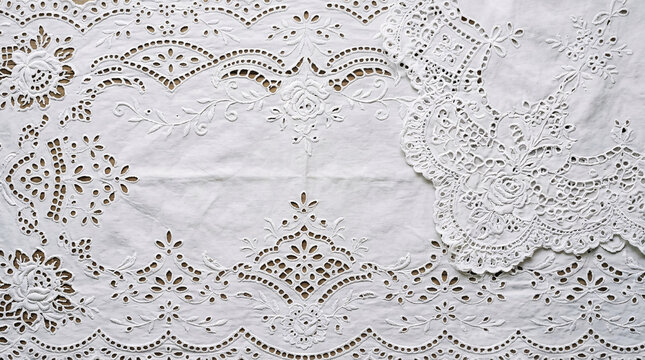 Elegant white cotton fabric featuring intricate broderie anglaise cutwork embroidery with floral and scalloped border patterns.