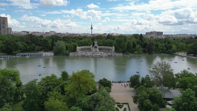 The Monument to Alfonso XII at El Retiro Park, Madrid, surrounded by lush greenery and a lively boating lake. Ideal for travel and tourism content.