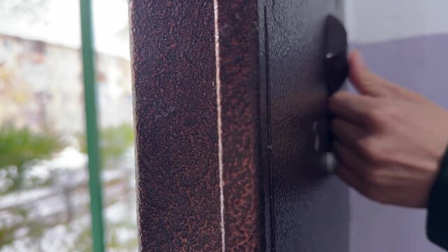 Person pressing door opening button on intercom panel close up outdoors, unlocking entrance door, access control action, security technology use
