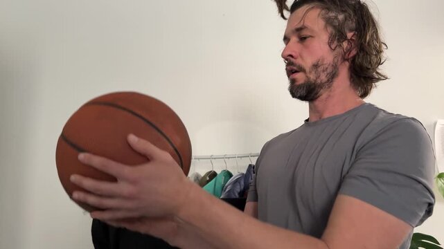 Man tossing basketball in air, sport activity and coordination concept, indoor movement and ball control training