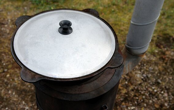 Cast iron kazan with lid on a traditional wood-burning stove outdoors