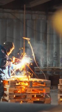 Contractors wearing safety gear work together, using a resistance welding device to join metal parts in a busy construction area, showcasing essential teamwork and precision in the welding process