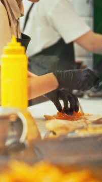 Culinary experts swiftly gather orders at the counter, while a waiter assists as they grill juicy burgers and crisp pitas, filling hungry street-food patrons with aromatic, fast-served meals
