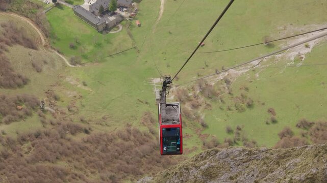 Red cable car descending picos de europa mountains