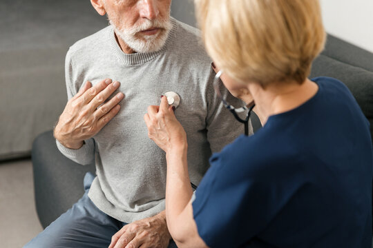 Doctor listens to heart of elderly man during health checkup at home