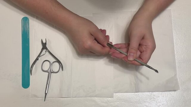 Preparing nails for a manicure: using a metal cuticle pusher for precise cuticle removal, top view
